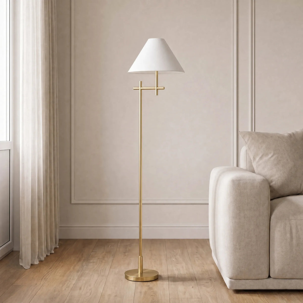 A modern floor lamp with a white tapered shade and a slim gold metal stand, styled in a minimalist living room next to a beige sofa.