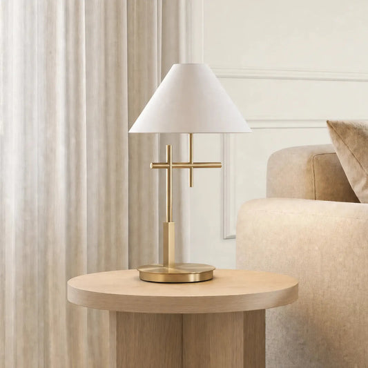A light oak wood side table with a modern three-leg base, styled in a living room next to a beige sofa with a white and gold table lamp on top.