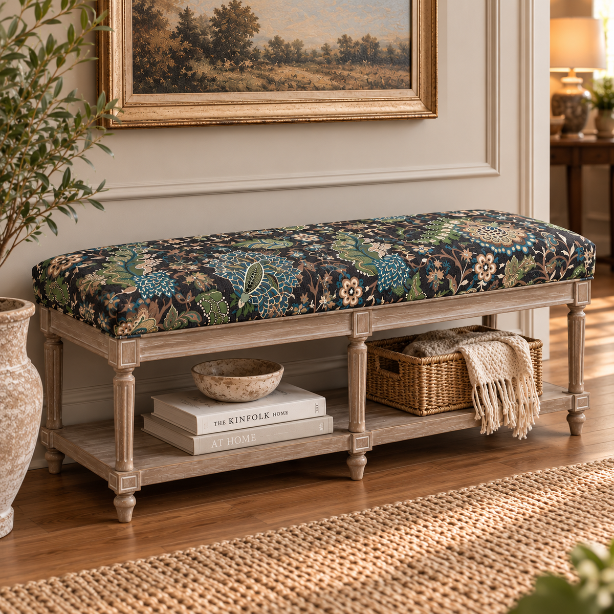 A rustic wooden entryway bench with a floral upholstered cushion in blue, green, and beige tones, styled in a warm living room setting with books, a basket, and a throw blanket.